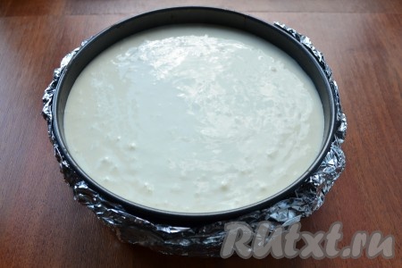 Творожную массу вылить поверх коржа из печенья. Дно и бока формы завернуть в 3 слоя фольги.