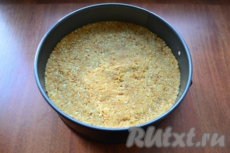 Разъемную форму диаметром 17-18 см застелить пергаментом (дно), выложить крошку из печенья и масла, хорошенько утрамбовать.