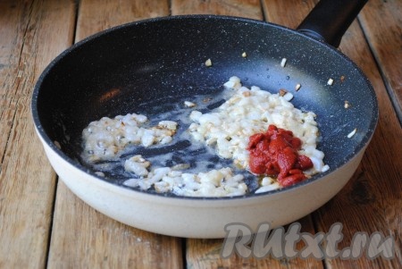 В мягкий и слегка золотистый лук всыпать 1 чайную ложку муки и хорошо перемешать, добавить томатную пасту и влить воду. 