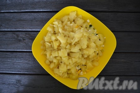 До готовности отварить картофель в мундире. Очистить от кожуры, нарезать кубиками и выложить в миску к остальным нарезанным продуктам.

