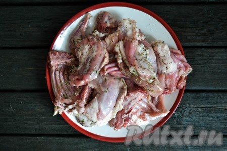 Посолить кусочки кролика, приправить прованскими травами и черным молотым перцем.
