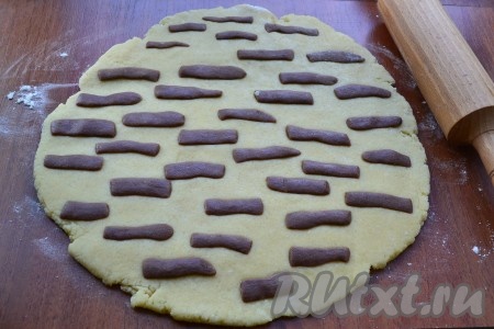 Светлое тесто раскатать, припылив стол мукой, в лепешку толщиной около 1 см. Отщипывая от тёмного теста небольшие кусочки, раскатывать их в тоненькие жгутики длиной около 3-4 см. Эти жгутики выложить на лепешку, чтобы получились полосочки.
