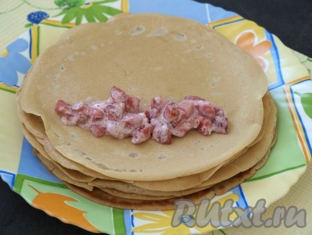 На край блинчика выкладывать по паре ложек смеси клубники и сметаны, затем сворачивать в трубочку.
