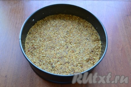 Снова включить блендер на несколько секунд, чтобы масло перемешалось с крошкой. Крошку пересыпать в разъемную форму диаметром 17-18 см, застеленную пергаментом (чуть смазать маслом), разровнять и хорошо утрамбовать. Поместить форму в холодильник.