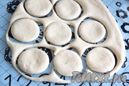 На силиконовом коврике или на столе, присыпанном мукой, раскатать тесто скалкой до толщины, примерно, 1,5 см. С помощью стакана вырезать из дрожжевого теста кружочки.
