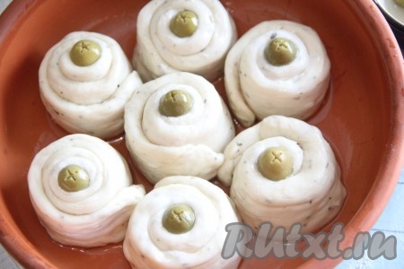 Закрутить тесто в рулетик, в центр поместить оливку. Выложить закусочные булочки в жаропрочную форму, смазанную растительным маслом. Дать несладким булочкам отдохнуть в течение 30 минут, а затем выпекать в разогретой духовке при температуре 200 градусов, примерно, 30 минут (до красивого золотистого цвета).
