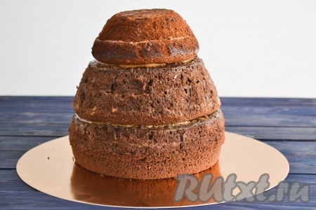 Каждый бисквитный корж разрезать на 2-3 части и обильно промазать между коржами кремом. Срезать углы, придавая будущему торту необходимую форму.
