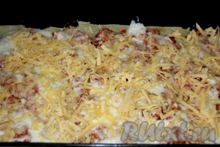 Затем выкладываем половину фарша, 1/3 соуса и половину порции сыра, натертого на терке.
