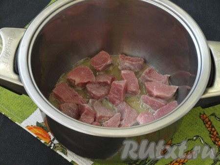 В кастрюлю с толстым дном, в которой будет готовиться картофель, налить подсолнечное масло и хорошо разогреть. В разогретое масло выложить кусочки говядины и обжарить мясо на среднем огне со всех сторон до золотистой корочки.