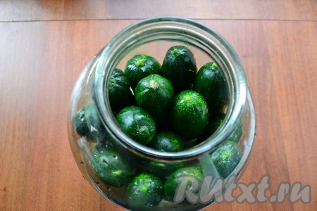 Далее банку наполовину заполнить огурцами.
