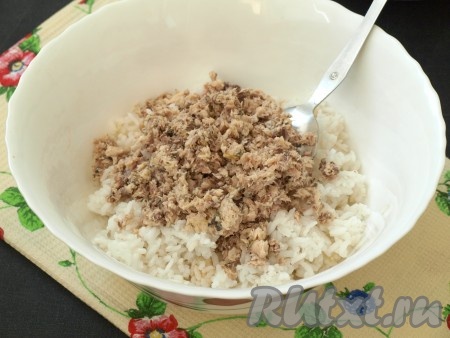 Если рис у вас сварился и успел остыть, то за это время можно успеть приготовить начинку. С рыбных консервов слить жидкость, размять вилкой и выложить к рису. Для того чтобы начинка для пирога получилась более сочной, в смесь консервов и риса можно добавить немного жидкости от консервов (но очень много жидкости не добавляйте, чтобы начинка не получилась жидкой).
