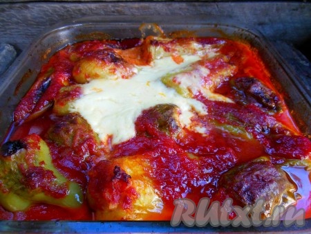 Отправьте перцы, фаршированные куриным фаршем, запекаться в предварительно разогретую до 170-180 градусов духовку на 40-50 минут (если используете стеклянную форму для запекания - отправляйте ее в холодную духовку). За 5-7 минут до готовности форму с перцем достаньте и положите сверху сметану (по 2-3 столовые ложки на каждую форму) и снова уберите в духовку.