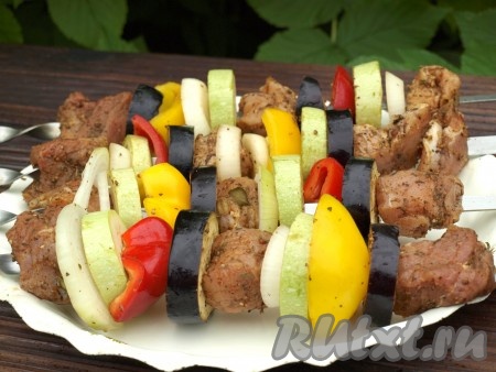 Разжечь мангал для приготовления шашлыков. Кусочки свинины и овощи посолить, нанизать на шампуры вперемежку.
