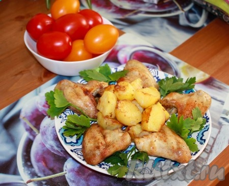 Минут за 20 до окончания приготовления куриных крылышек с картофелем, добавить лук и чеснок, всё перемешать и отправить запекать в духовку до готовности. Подавать со свежими овощами, зеленью.