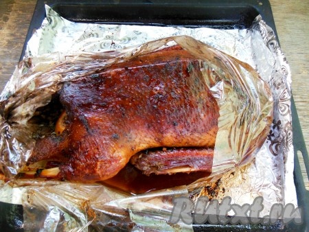 Запекайте утку в разогретой духовке около 1,5-2 часов при температуре 170 градусов. Затем аккуратно разрежьте рукав для запекания и проверьте мясо на готовность - мякоть птицы должна легко прокалываться ножом.