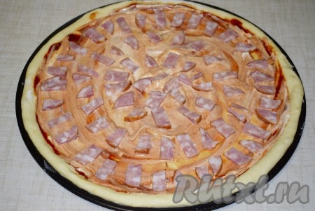 Затем добавить майонез и равномерно распределить его по тесту. Выложить колбасу, нарезанную на полоски.
