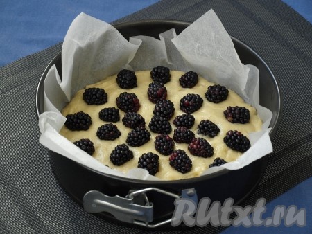 Форму диаметром 22 см застелить пергаментом, далее выложить половину теста. Промытые и обсушенные ягоды ежевики разложить на поверхности теста.
