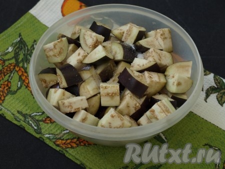 Баклажаны нарезать крупными кубиками толщиной около 1,5 см, хорошо посолить и перемешать. Залить водой так, чтобы она покрыла баклажаны, сверху положить тарелку с грузом, чтобы овощи не всплывали, и оставить на 20 минут.