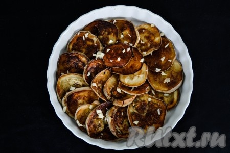 В форму для запекания в произвольном порядке выложить баклажаны, смешанные с чесноком.
