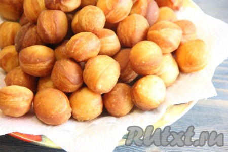 Готовые пончики из дрожжевого теста достать из масла и выложить на бумажное полотенце, чтобы удалить лишнее масло.
