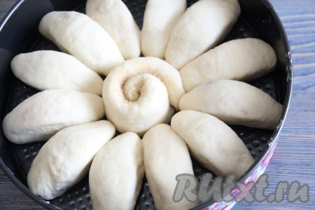 Форму для выпечки смазать растительным маслом. Выложить яблоки в тесте швом вниз в виде цветка. Серединку отрывного пирога можно заполнить улиткой из теста. Накрыть дрожжевой пирог полотенцем и оставить в тепле на 30-40 минут.