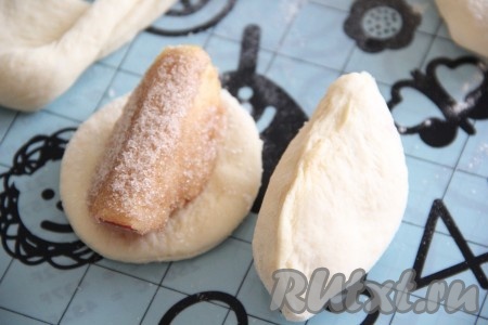 Выложить на каждый кружочек теста дольку яблока и завернуть в тесто, хорошо скрепляя края.