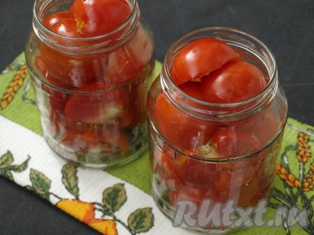Тщательно вымыть банки и простерилизовать их над паром. На дно каждой банки положить по веточке укропа и по 2 зубчика чеснока, наполнить банки половинками помидоров. Вместо веточек укропа можно положить зонтики небольшого размера.
