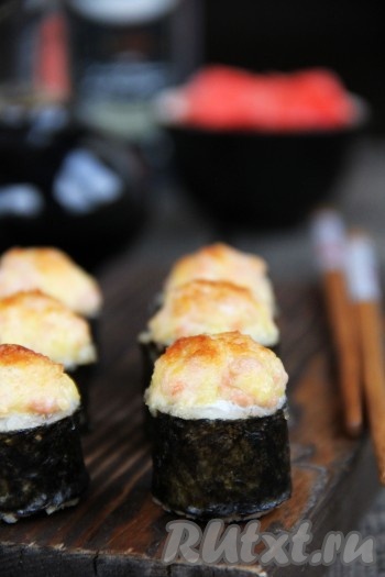 Запекать вкусные роллы в разогретой духовке при температуре 200 градусов при верхнем нагреве, примерно, 10 минут. Поверхность шапочки должна покрыться красивой золотистой корочкой. Подать приготовленные запечённые роллы в горячем виде с соевым соусом и имбирём.