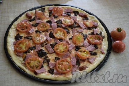 Сверху колбасы и грибов выкладываем помидоры, нарезанные кружочками.
