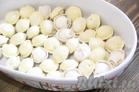 На дно жаропрочной формы выложить замороженные пельмени и разровнять в один слой.
