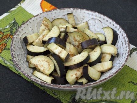 Полукружками нарезать баклажаны, сложить в миску и посолить.
