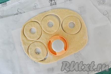 Формочкой вырезать пончики. Излишки теста убрать, а сами пончики накрыть салфеткой и оставить на 20 минут, чтобы они подошли.
