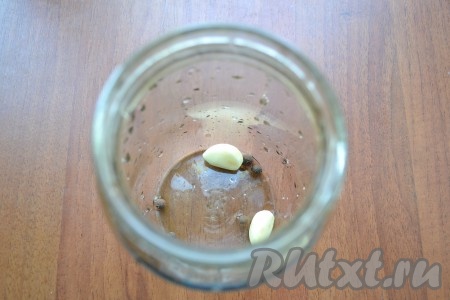 На дно чистой банки поместить зубчики чеснока и душистый перец.
