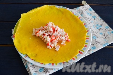 В центр каждого яичного блина выложить начинку из крабовых палочек, сыра и чеснока.
