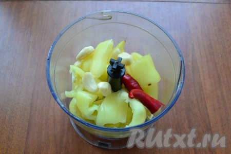 В чашу блендера поместить нарезанный сладкий перец, зубчики чеснока и перец чили.
