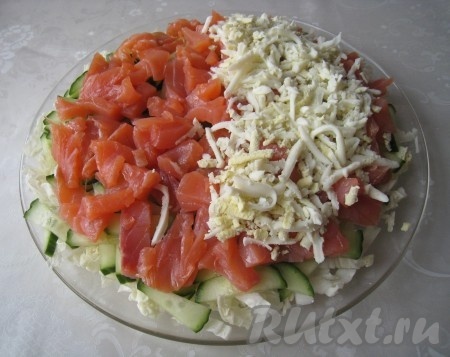 Следующим слоем выложить нарезанную кусочками красную рыбу, а на неё - яйца, натёртые на крупной тёрке.
