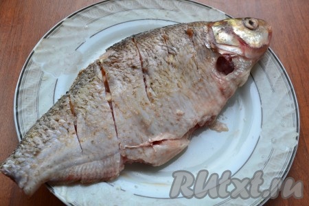 Тушки леща посолить немного снаружи и внутри. В надрезы вложить кусочки очищенного чеснока.
