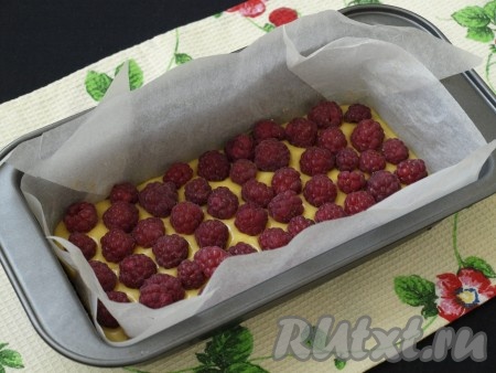 Я решила выложить 2 слоя малины. Форму застелить пергаментом, углы подрезать, чтобы пергамент ложился ровно. Треть теста вылить в форму, разложить на поверхности сухую свежую малину, затем вылить ещё половину оставшегося теста и ещё один слой малины (можно выложить чуть меньше малины, чем в первом слое).
