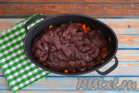 Говяжью печень вымыть, зачистить от пленки и прожилок, нарезать небольшими кусочками и выложить в казан к овощам. 