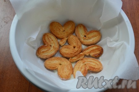 Далее любую круглую форму застелить пергаментом так, чтобы края пергамента свисали с краёв формы, выложить в один слой печенье "Ушки".