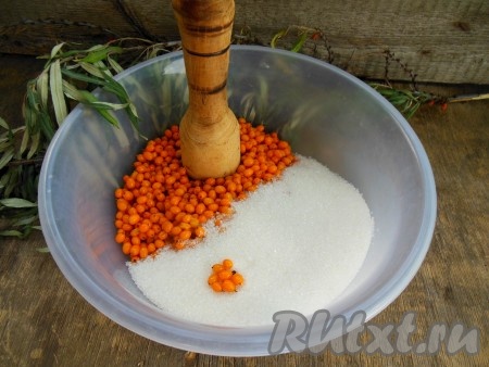 Разотрите сахар с облепихой при помощи деревянной толкушки.
