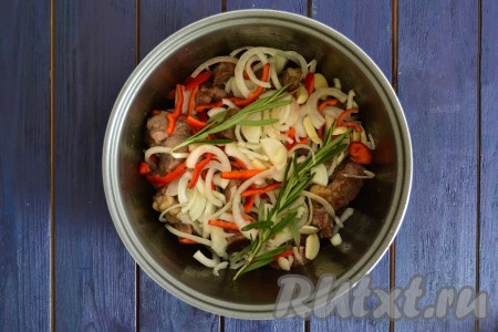 Очистить репчатый лук и нарезать тонкими полукольцами. Перец, очистив от семян и плодоножки, нарезать соломкой. Очищенные зубчики чеснока нарезать пластинами. Лук, чеснок и сладкий перец выложить к мясу. По желанию, добавить 1-2 веточки розмарина. Перемешивая все содержимое, обжарить еще 2-3 минуты.
