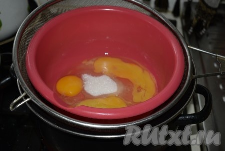 Я ставлю большую кастрюлю на огонь, наливаю на дно немного воды и жду, пока она закипит. Затем в кастрюлю помещаю дуршлаг и уже на него ставлю миску с яйцами и сахаром.

