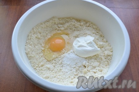 Все перемешать, добавить нарезанное небольшими кусочками или натертое на крупной терке холодное сливочное масло. Растереть все в крошку. Добавить яйцо, разрыхлитель и сметану.
