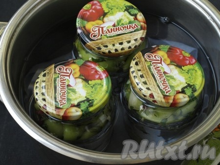 В кастрюлю на дно постелить салфетку, сложенную в 2-3 раза, и поставить на неё банки с помидорами. Прикрыть банки крышками, ошпаренными кипятком. Залить в кастрюлю холодную воду до плечиков банок и поставить на огонь. С момента закипания стерилизовать банки с помидорами 10 минут на среднем огне, литровые банки стерилизовать 15 минут. Параллельно вскипятить воду в чайнике и в самом конце в каждую банку долить кипяток. Банки с помидорами сразу же закрутить или закатать, перевернуть и укутать тёплым пледом до полного остывания.
