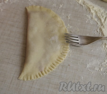 Затем проходимся по краю чебурека вилкой (делаем это для того, чтобы чебуреки получились симпатичными и чтобы края не разошлись во время жарки).

