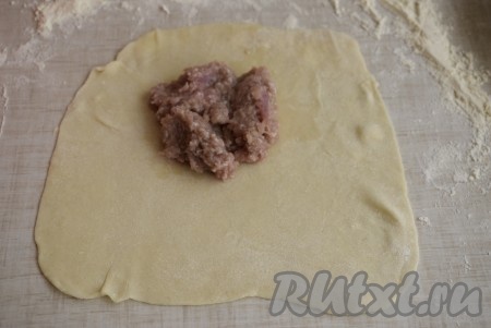 На каждый раскатанный кусочек теста на одну сторону пласта кладем 1 столовую ложку фарша.
