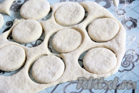 Поверхность стола присыпать мукой. Скалкой раскатать на столе тесто в пласт толщиной, примерно, 1-1,5 сантиметра. Затем вырезать кружочки с помощью стакана.