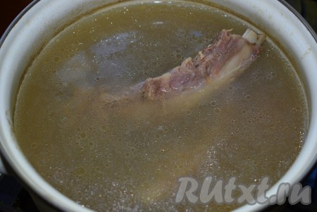 Ставим кастрюлю на огонь и варим бульон до закипания на среднем огне. С момента закипания снимаем пену шумовкой и убавляем газ. Варим бульон на медленном огне до готовности мяса (не менее двух часов). По истечении времени готовое мясо вынимаем из супа, если нужно, процеживаем бульон. Вареные лук и морковь достаём из бульона, они нам больше не понадобятся. Мясо отделяем от кости и нарезаем на порционные кусочки, в дальнейшем это мясо будем добавлять в тарелки с супом.