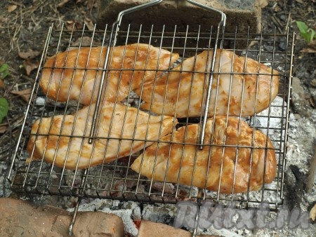 Разжигаем мангал и ждём, когда прогорят дрова до седых углей. Решётку с куриными грудками выкладываем на мангал.
